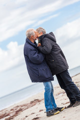 happy elderly senior couple walking on beach