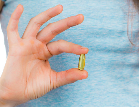 Fingers holding a fish oil capsule