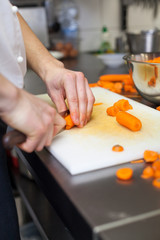 Chef in uniform preparing fresh carrot batons