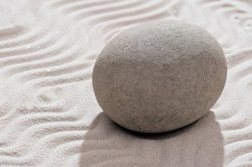 Fototapeta na wymiar gray smooth stone in the garden on the sand