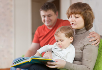 Obraz premium Happy parents with child looks the book