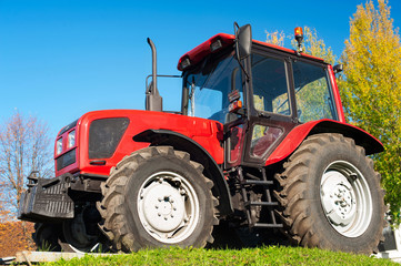 Modern red tractor on a blue sky background