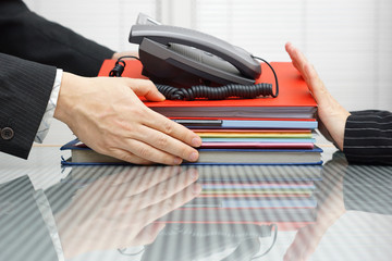 businessman is receiving files,folders  and telephone from cowor