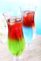 Glasses of cocktails on table on light blue background