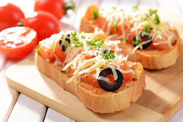 Delicious bruschetta with tomatoes on cutting board close-up