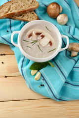 Mushroom soup in pot, on napkin,  on wooden background