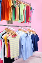 Fototapeta premium Different clothes on hangers, on pink background