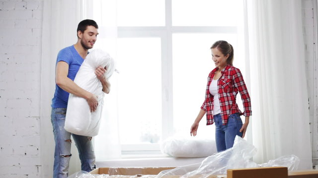 smiling couple opening big cardboard box with sofa