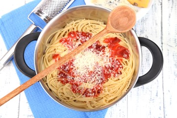 Composition with tasty spaghetti in pan, grater, cheese,