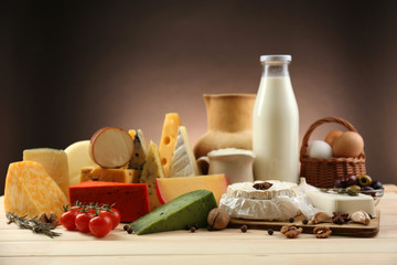 Tasty dairy products on wooden table, on dark background