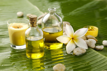 frangipani and stones with yellow candle on wet banana leaf