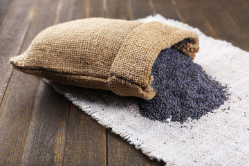 Poppy seeds in sack on table close-up