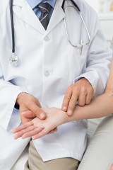 Mid section of a doctor taking a patients pulse