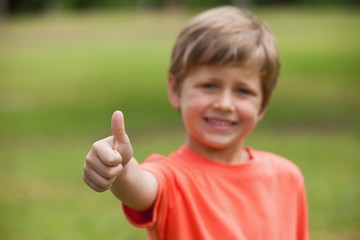 Smiling young boy gesturing thumbs up at park