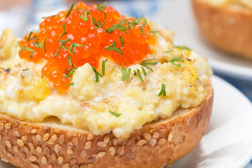 scramble eggs with red caviar on a bun close-up