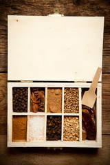 Assortment of spices in wooden box on old wooden table