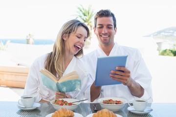 Couple with book and digital tablet on breakfast table