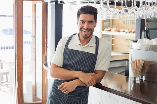 Portrait of a smiling young waiter at cafe counter