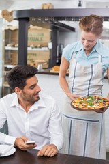 Fototapeta na wymiar Waitress giving pizza to a man at coffee shop