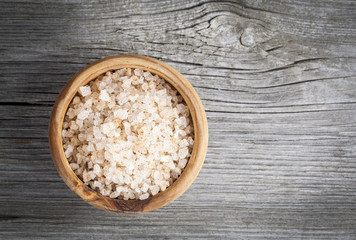 Pink salt in the wooden bowl, on wooden board