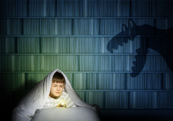 boy under the covers with a flashlight