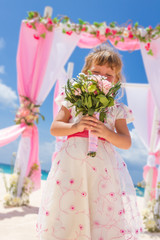 young happy kid girl in beautiful dress on tropical wedding setu