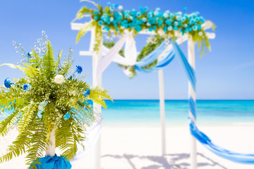 Obraz premium wedding arch decorated with flowers on tropical sand beach, outd