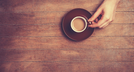 Female hands holding cup of coffee.