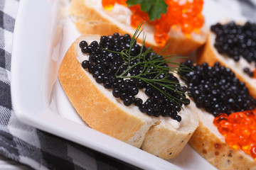 sandwiches with black and red caviar on a plate macro.