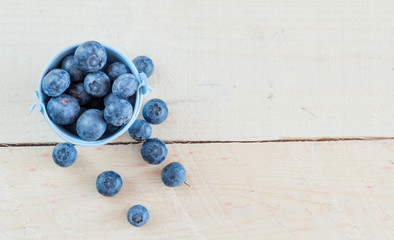 Fresh blueberries in white bowl on wood table, rustic style 