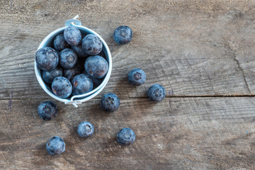 Fresh blueberries in white bowl on wood table, rustic style