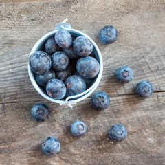 Fresh blueberries in white bowl on wood table, rustic style