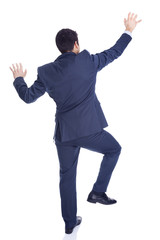 Handsome businessman climbing a wall, isolated on white