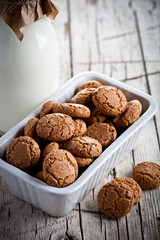 meringue almond cookies in a bowl and bottle of milk