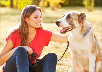 Portrait of a woman with her beautiful dog lying outdoors