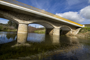 View of a small modern cement bridge over a small river.