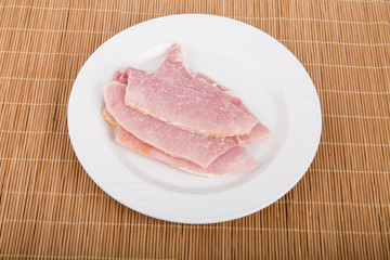 Slices of Ham on White Plate and Bamboo Mat