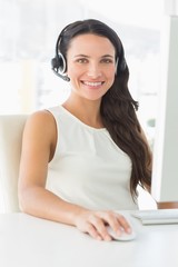 Smiling call centre agent sitting at her desk