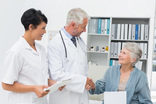 Smiling female patient and doctor shaking hands