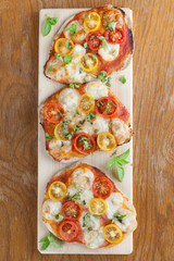 Mini pizzas with mozzarella, cherry tomatoes and basil