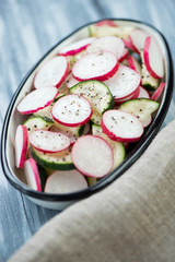 Salad with radish and cucumber in an enameled bowl, close-up