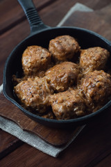 Frying pan with meatballs, rustic wooden background, close-up