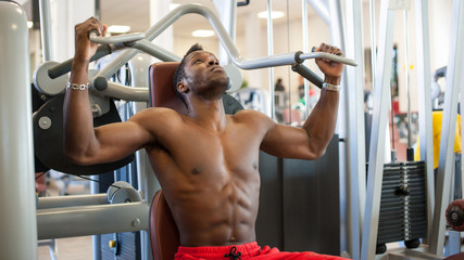 Fototapeta na wymiar Strong young black man exercising at the gym.