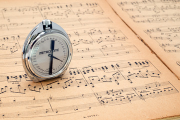 Pocket metronome  on an ancient music score background
