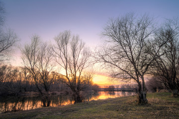 Fototapeta na wymiar Old country road on lake at the autumn sunset light