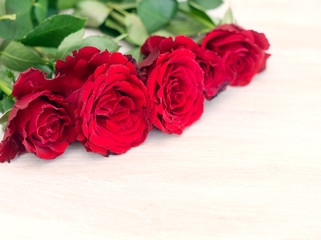 some bright red roses on a white wooden table