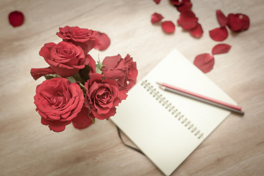 retro image in soft focus, red roses and notebook with pencils o