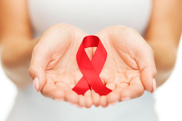 hands holding red AIDS awareness ribbon - obrazy, fototapety, plakaty