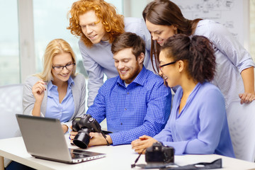 smiling team with laptop and photocamera in office
