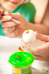 Closeup shot of woman and girl drawing flowers on easter eggs